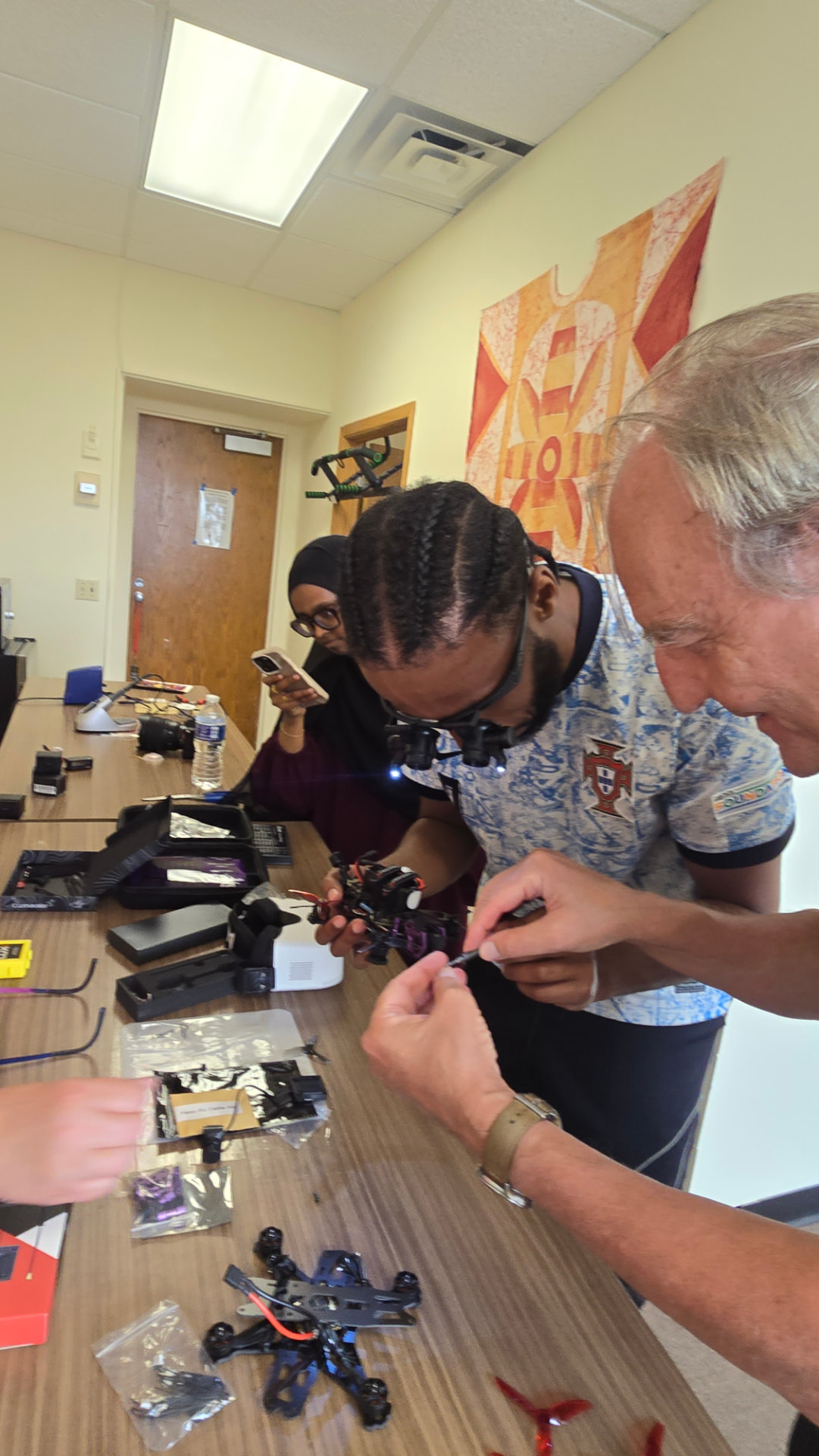 A young participant and an instructor work together to assemble components on a small drone during an 846s.org workshop.